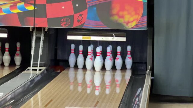 Person throwing a bowling ball that misses the pins at an indoor bowling alley during a casual recreational game.