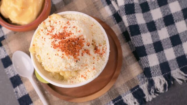 Rotating view of traditional Mexican snack esquites served on a wooden plate with limes