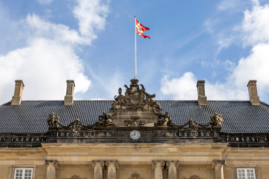 The ornate facade of Amalienborg Palace in Copenhagen with the Danish flag flying high.