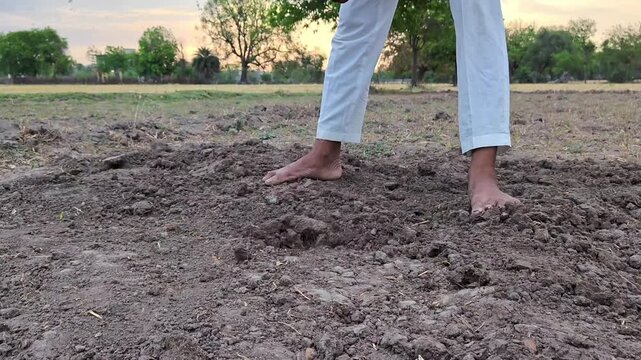 Farmer digging dry soil with a hoe tool in agricultural field