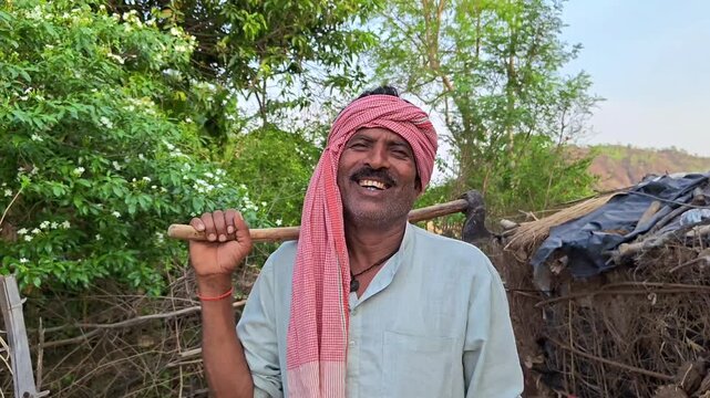 Smiling indian farmer holding an axe on his shoulder