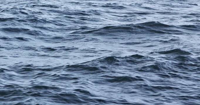Close view of blue ocean surface with rolling waves ripples and soft motion Calm marine water texture with cool tones natural movement and peaceful seascape background for travel nature and design