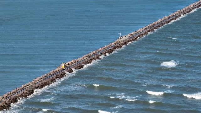 Static telephoto view of the rocky breakwater and sail bogey at Molhes da Barra in Rio Grande, Brazil.
