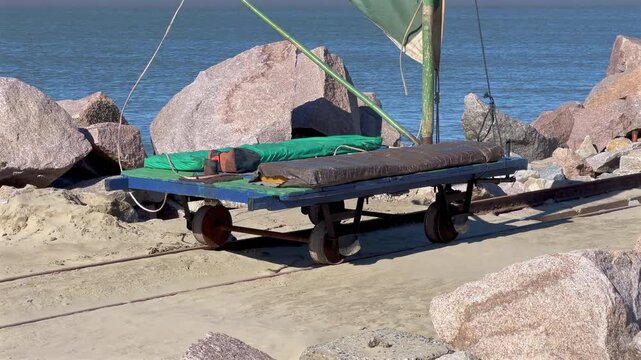 Static view of a sail bogey parked on rail tracks atop a stone breakwater in Rio Grande, Brazil.