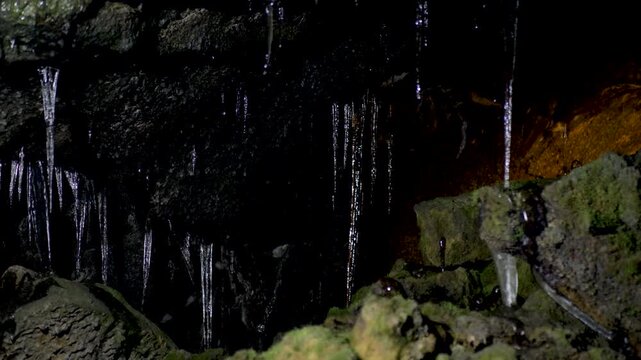 Slow motion close-up of ice formations and frozen icicles hanging from a rocky roof inside a dark underground lava wind cave near Aokigahara Forest in Mount Fuji Yamanashi Japan Asia nature tourism