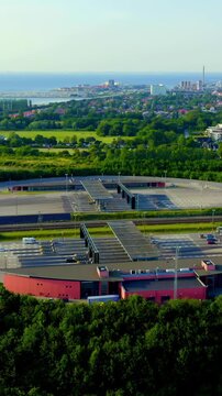Vertical video. Malmo, Sweden. Oresund Bridge toll plaza at Lernacken, Drone footage over the multi-lane payment gates and approaching highway, with the city and coast visible in the distance under c