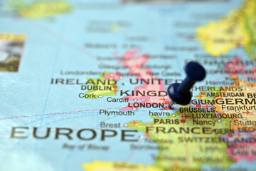 Blue Push Pin Highlighting London on Vintage Paper World Map Macro Close Up © BlueMistFilmStudios