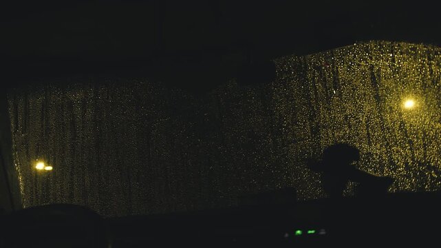 Car windshield wipers cleaning rain at night