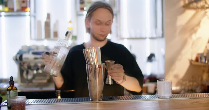 Mixing beverage. Barkeeper counter. Man professionally adding alcohol color flavored syrup with jigger to shaker preparing cocktail.