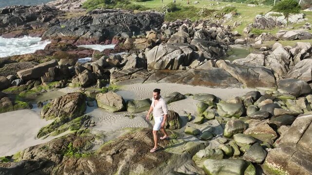 Ponta das Campanhas, Armacao in Florianopolis. A man walks across the island among the rocks. Aerial view.