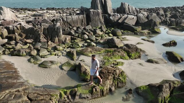 Ponta das Campanhas, Armacao in Florianopolis. A man walks across the island among the rocks. Aerial view.