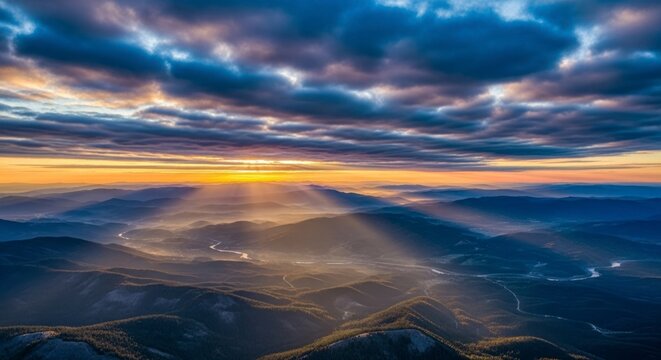 Dramatisch zonsonderganglandschap met zonnestralen die door de wolken boven de bergen breken.