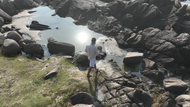 Ponta das Campanhas, Armacao in Florianopolis. A man walks across the island among the rocks. Aerial view 