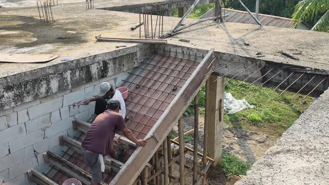 Construction footage of two workers assembling staircase formwork and reinforcement before concrete pouring.