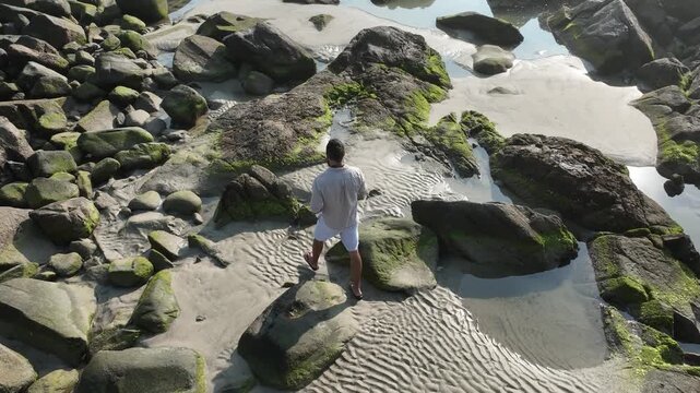 Ponta das Campanhas, Armacao in Florianopolis. A man walks across the island among the rocks. Aerial view 