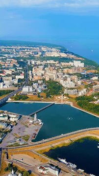 Vertical video. Cheboksary, Russia. Mother Patroness Monument, a 46-meter copper-clad figure with outstretched arms overlooking Cheboksary Bay and the Volga River, Drone footage under clear summer sk
