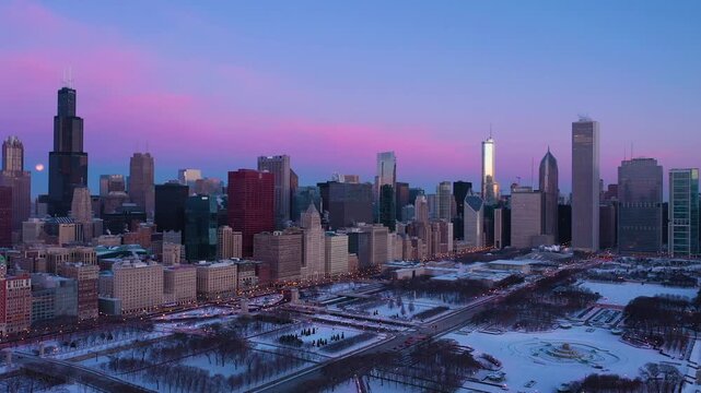 Stunning aerial hyperlapse captures chicago downtown cityscape at colorful sunset with full moon in winter.