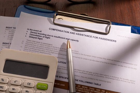 High angle view of Smartwings compensation and assistance for passengers form on a clipboard with a silver pen and a calculator on a wooden desk