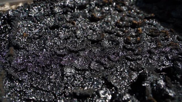 Heavy soot buildup inside fireplace chamber close up. Thick creosote and carbon deposits on dirty cast iron stove interior