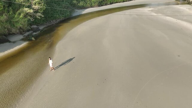 Ponta das Campanhas, Armacao in Florianopolis. A man walks across the island among the rocks. Aerial view 