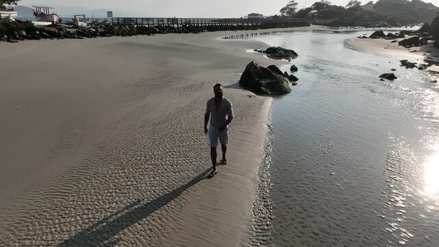 Ponta das Campanhas, Armacao in Florianopolis. A man walks across the island among the rocks. Aerial view 