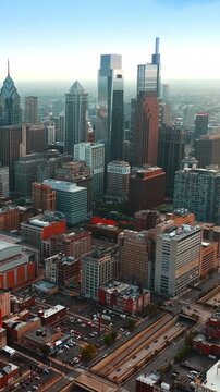 Aerial drone video of Philadelphia skyline at sunset with city buildings and traffic on highway during golden hour.