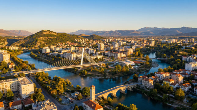 Panoramic view of Podgorica, Montenegro, with the Moraca River and bridges under a clear blue sky.