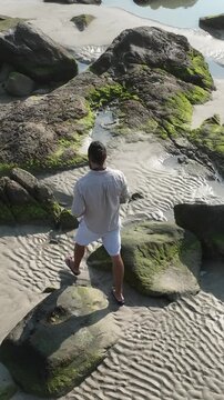 Ponta das Campanhas, Armacao in Florianopolis. A man walks across the island among the rocks. Aerial view.