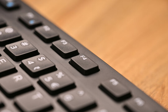 Side Angled Top View Macro Close-Up Black Computer Keyboard Highlighting F4 Function Key on Blurred Tech Background