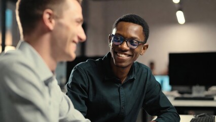 Fototapeta premium Two men discussing and smiling in open office environment