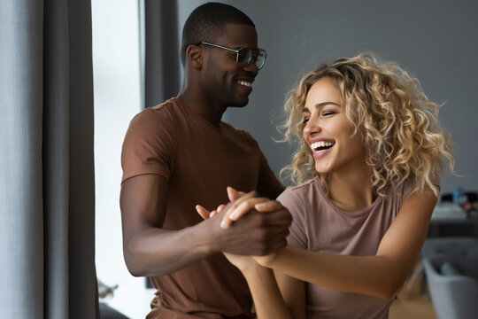happy couple dancing in the living room, they both laughing while dances to the music