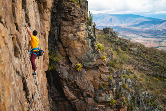 woman rock climbing in Tarija, Bolivia is visible on the left side of the cliff wall