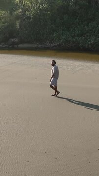 Ponta das Campanhas, Armacao in Florianopolis. A man walks across the island among the rocks. Aerial view.