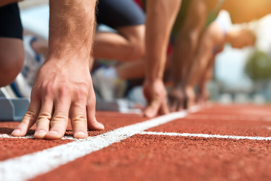 sprinters in starting position on a track, focusing on their hands and feet, ready for the start of the race