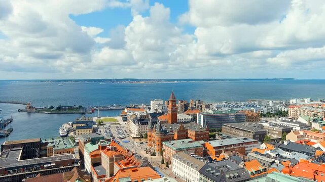 Helsingborg, Sweden. Helsingborg Town Hall, a red-brick neo-Gothic landmark with a 65-meter clock tower, Drone footage over the Oresund strait on a bright summer day. Drone footage