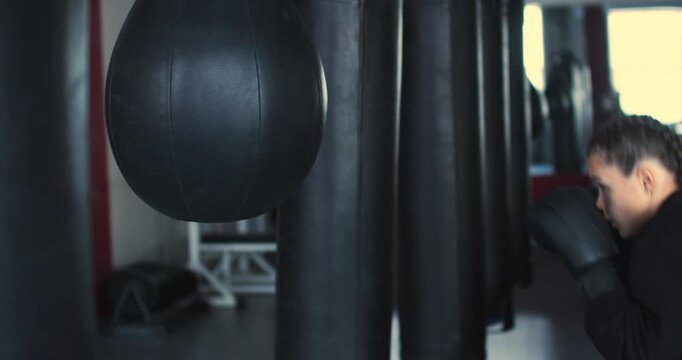 Watch a teenage girl boxer deliver rapid, powerful punches to the punching bag, demonstrating her dedication and commitment to mastering the sport. Slow motion 4k footage.