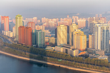 Naklejka premium Panoramic view of Pyongyang from Yanggakdo Hotel. Taedong River in morning fog. Ryugyong Hotel and modern residential complex upstream. Atmospheric, calm, iconic. Pyongyang, North Korea
