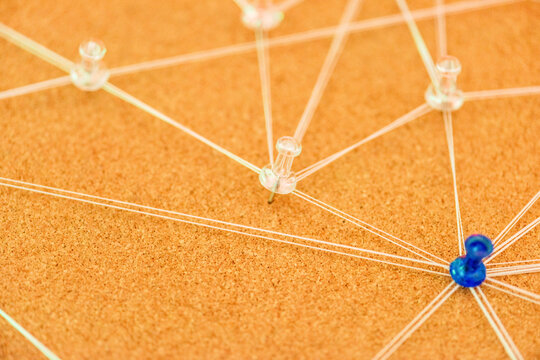 Close-up of connected pins and threads on an orange board, abstract network