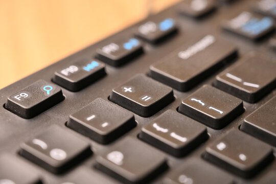 Black Computer Keyboard Macro Shot Highlighting Equals and Plus Key with Soft Blurred Background Angled Top View