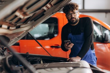 Mechanic using phone checking car engine in auto service © Roman