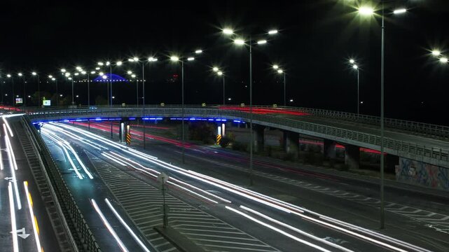 Timelapse of cars moving at night on a bridge, headlights of cars on the road