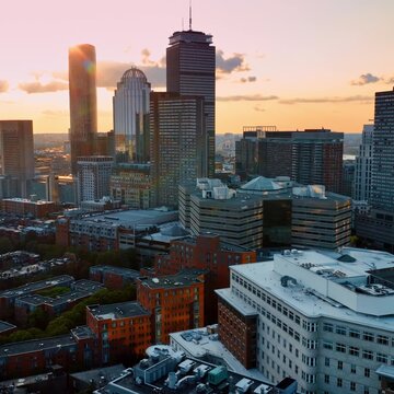 Cinematic aerial view of Boston skyline at sunset featuring Prudential Center and Christian Science Plaza.