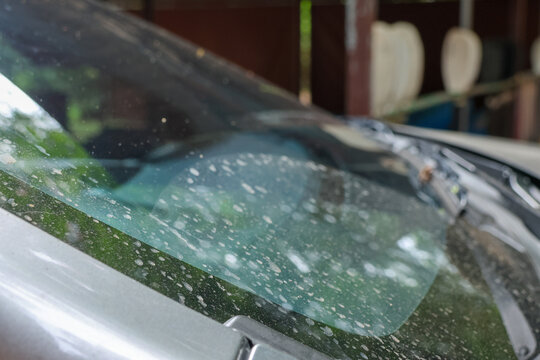 Close up view of dirty car windshield with water spots and streaks over glass surface showing neglect and needing thorough wash, creating slightly melancholic and dull feeling overall
