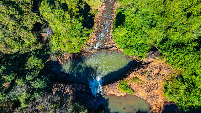 Scenic tropical landscape of Tad Pha Suam Waterfall in Laos. The flowing stream passes through dramatic rock formations and dense green forest captured from above in an aerial nature travel photograph