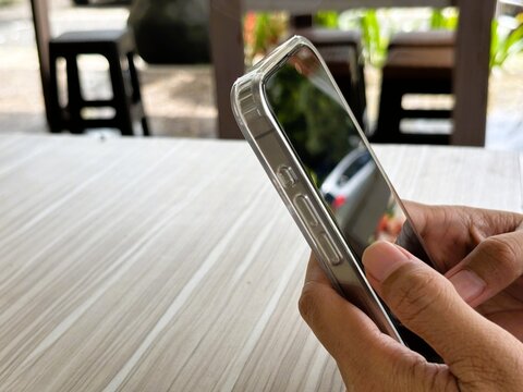 An Asian woman holds a cell phone with a specially designed tempered glass screen protector that uses polarizing optical coating technology to make it difficult to spy on.