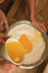 Fototapeta premium Pouring egg mixture into flour while baking together at home
