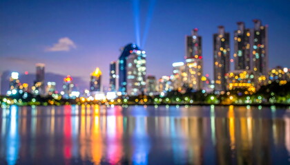 Obraz premium Blurred Cityscape Lights Reflecting on Lake Water at Night