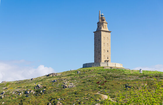The Tower of Hercules ancient Roman lighthouse on a green hill under blue sky in A Coru&ntilde;a Galicia, Spain