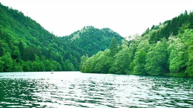 View of a lake with water moved by the current. Mountains full of trees line the banks. Lake Levico is a lake in Trentino, Italy. It is located in the municipality of Levico Terme