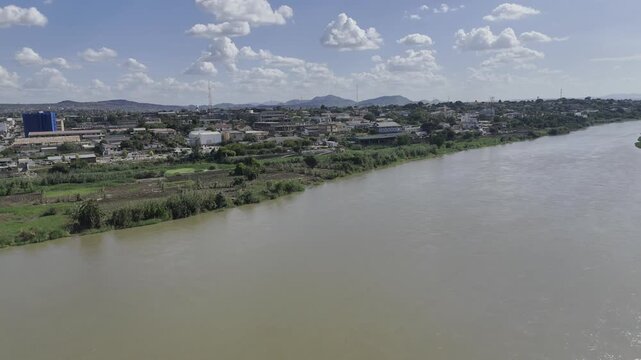 Drone flies backwards over Zambezi River to reveal Samora Machel Bridge connecting the two banks on a sunny day in Tete, Mozambique